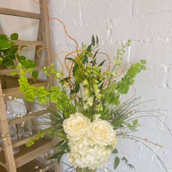 White roses and hydrangeas in a clear vase with green accents