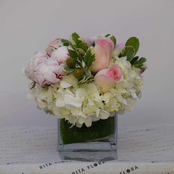 Pink and white floral arrangement in a square glass vase