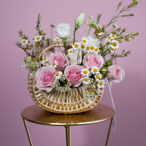 Pink roses and white daisies in a woven basket