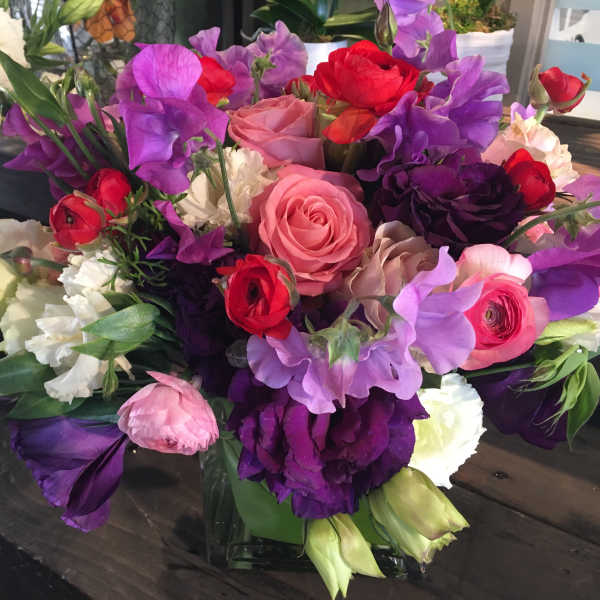 Mixed bouquet of pink, purple, red, and white flowers in a low vase