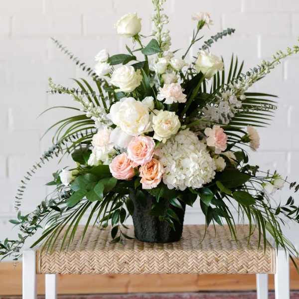 White and blush floral arrangement in a black vase