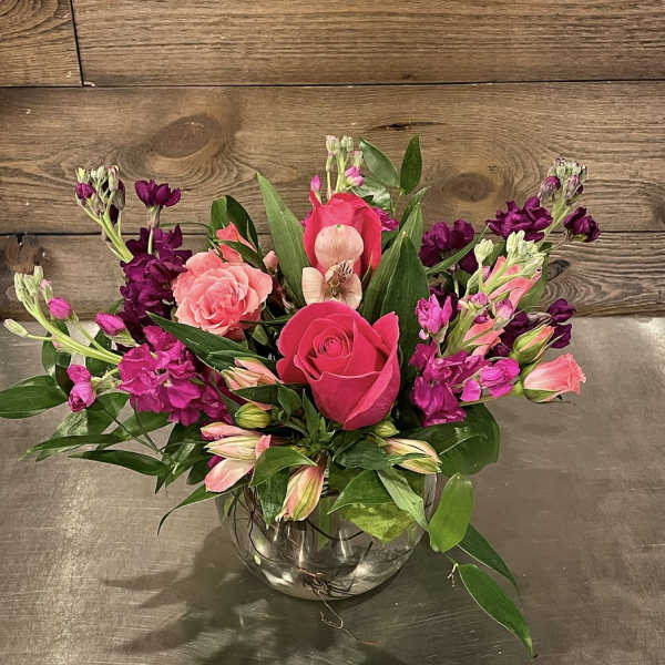 Pink and purple floral arrangement in a clear glass bowl vase