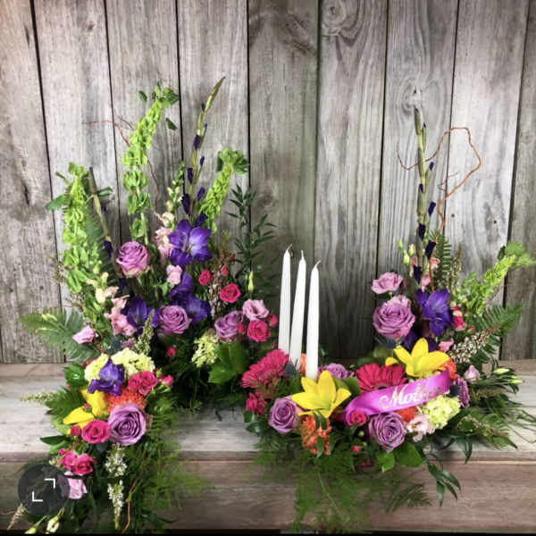 Colorful floral arrangement with candles and a pink ribbon