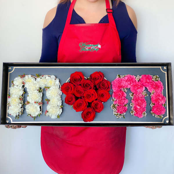 Framed floral display spelling M O M with white, red, and pink flowers