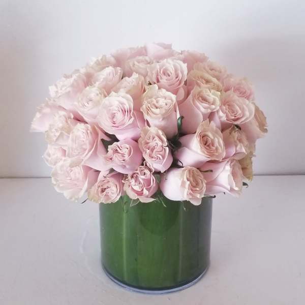 Bouquet of pale pink roses in a green cylindrical vase