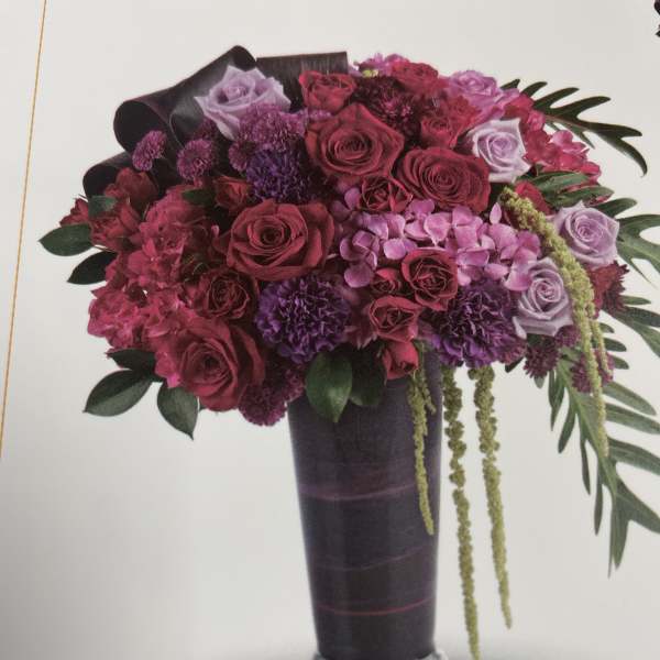 Bouquet of pink and purple roses in a tall dark vase