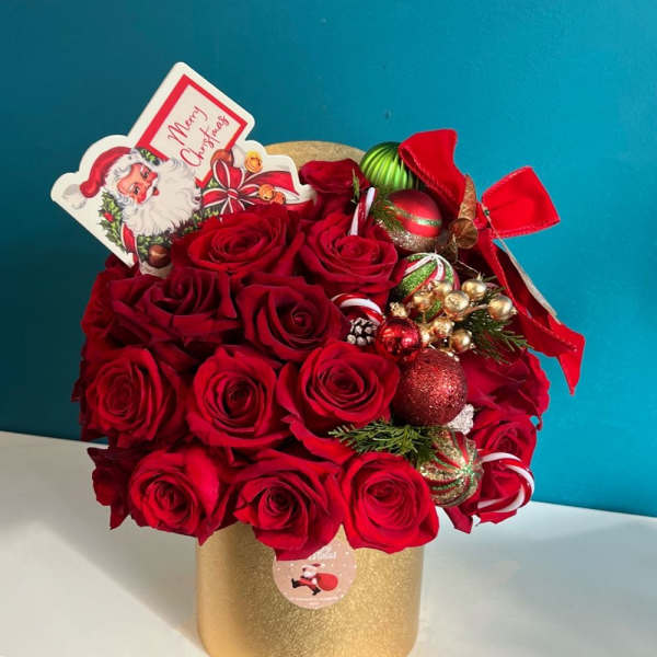 Red roses arranged in a gold box with Christmas ornaments and a Santa card