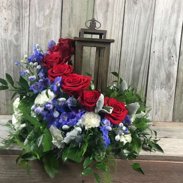 Red roses and blue flowers arranged around a lantern