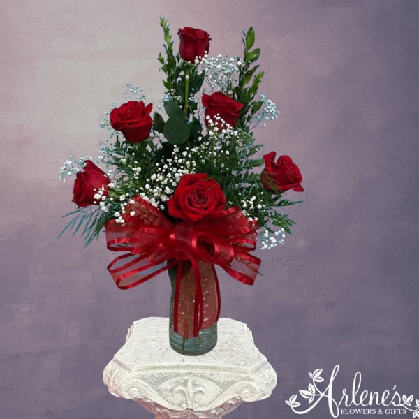 Red roses in a glass vase with a red ribbon bow