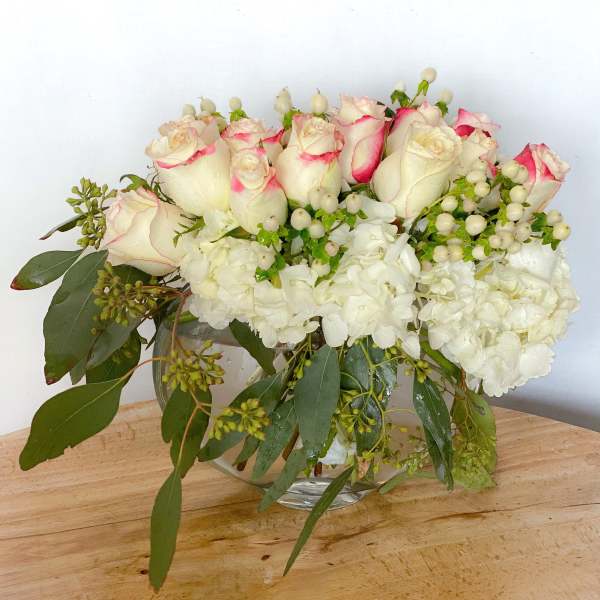 White and blush roses with white hydrangeas in a glass vase