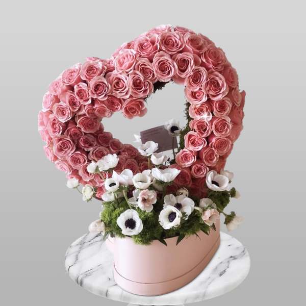 Heart-shaped pink rose arrangement with white anemones in a pink box