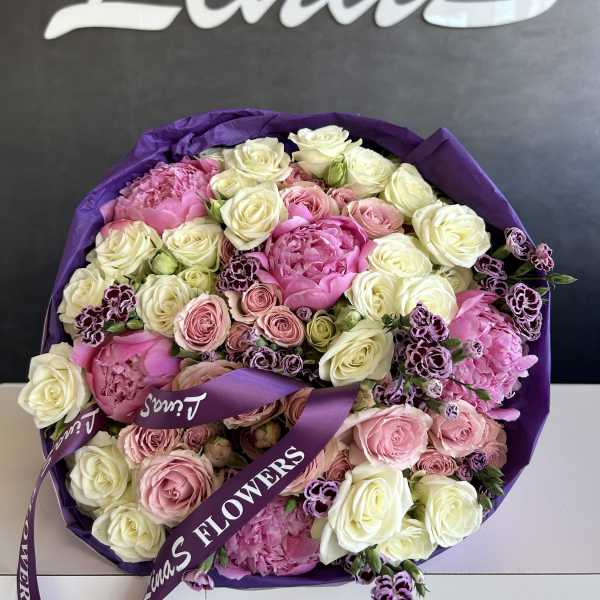 Round bouquet of pink and white roses with purple wrapping