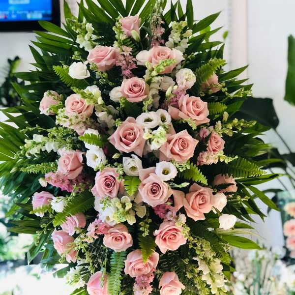 Large standing spray of pink roses and white blooms with greenery