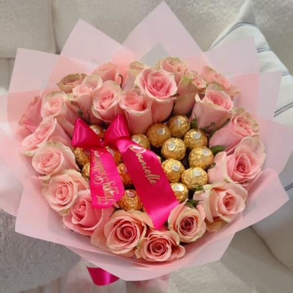 Pink rose bouquet with gold-wrapped chocolates and a satin ribbon