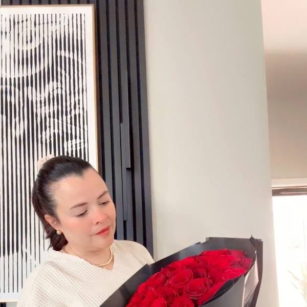 Woman holding a bouquet of red roses wrapped in black paper