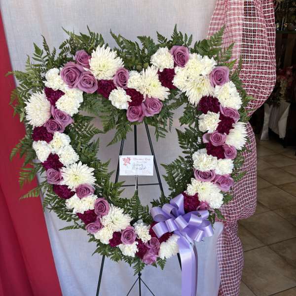 Heart-shaped floral wreath with pink roses and white chrysanthemums on an easel