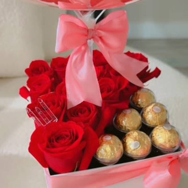 Red roses and gold chocolates in a pink ribboned gift box