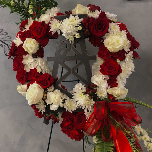 Red and white floral wreath on a black easel with a red ribbon