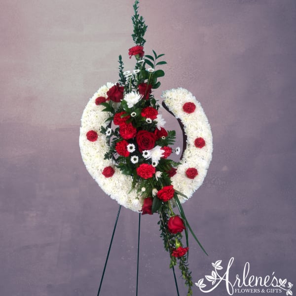 Red and white funeral wreath on a stand with roses and carnations