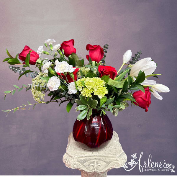 Red roses and white tulips in a red glass vase