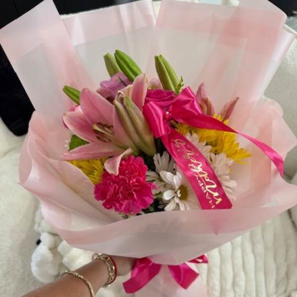 Pink lily bouquet wrapped in pale pink paper with a bright ribbon