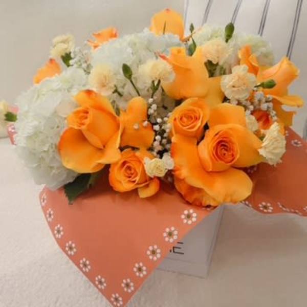 Orange roses and white flowers in a wrapped bouquet