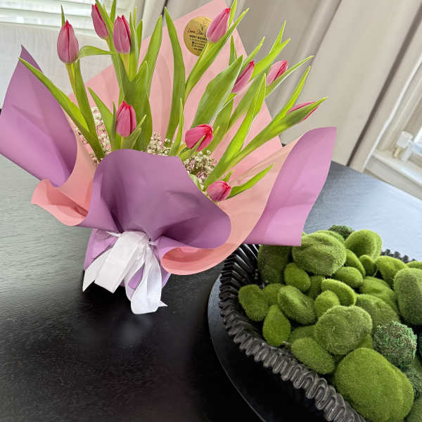 Pink tulips wrapped in pink and purple paper on a table