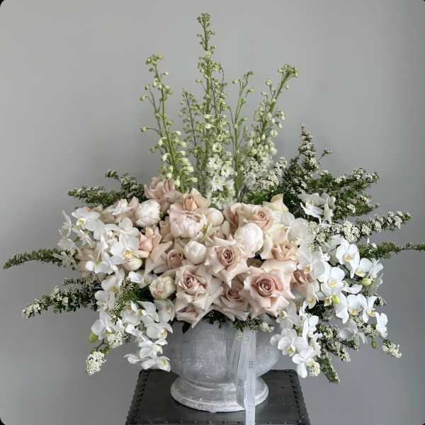 Large pale pink and white floral arrangement in a gray vase
