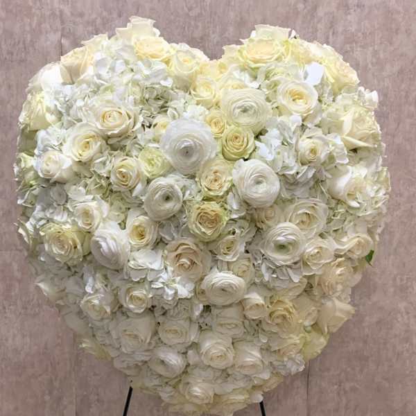 Heart-shaped standing arrangement of white and cream roses and hydrangeas on a metal easel
