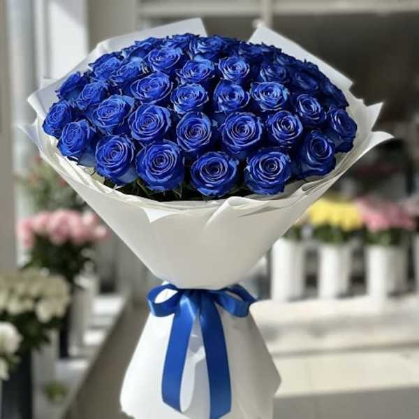 Bouquet of blue roses wrapped in white paper with a blue ribbon