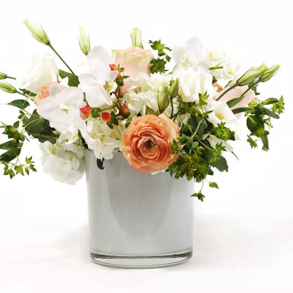 Mixed white and peach flowers arranged in a clear glass vase