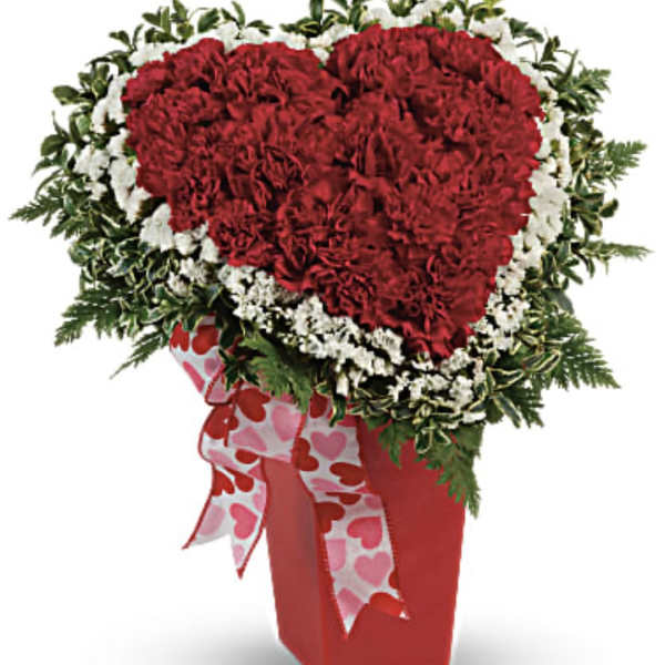 Heart-shaped red carnation arrangement with white flowers and a heart-print ribbon