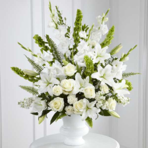 White floral arrangement in a white vase with green accents