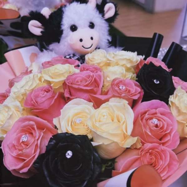 Bouquet of pink, cream, and black roses with a plush cow toy