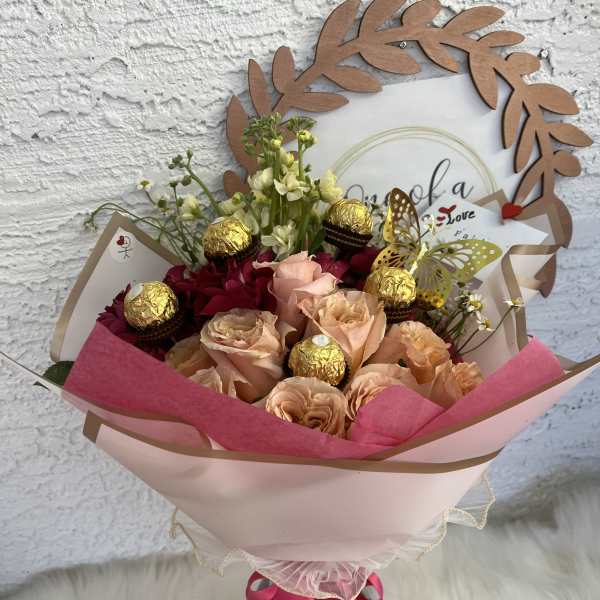 Bouquet of peach and red roses with gold chocolates and a butterfly topper