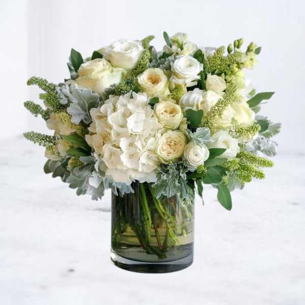 White roses and hydrangeas arranged in a glass vase