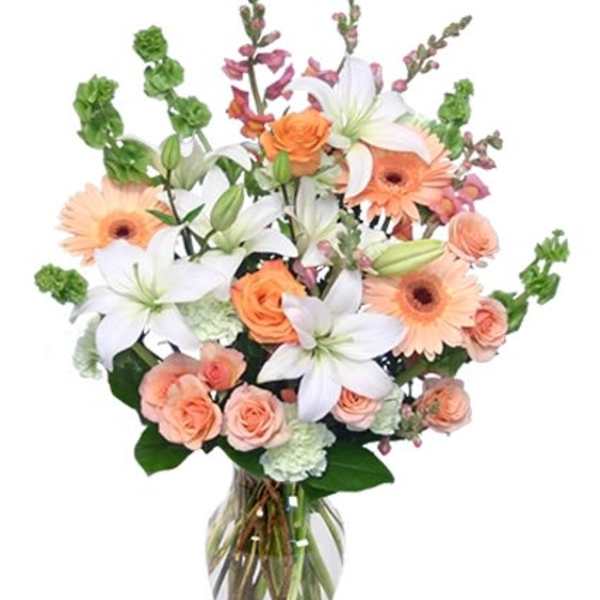 Peach and white flower bouquet in a clear glass vase