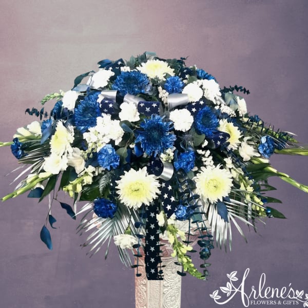 Blue and white floral spray with ribbon on a pedestal stand