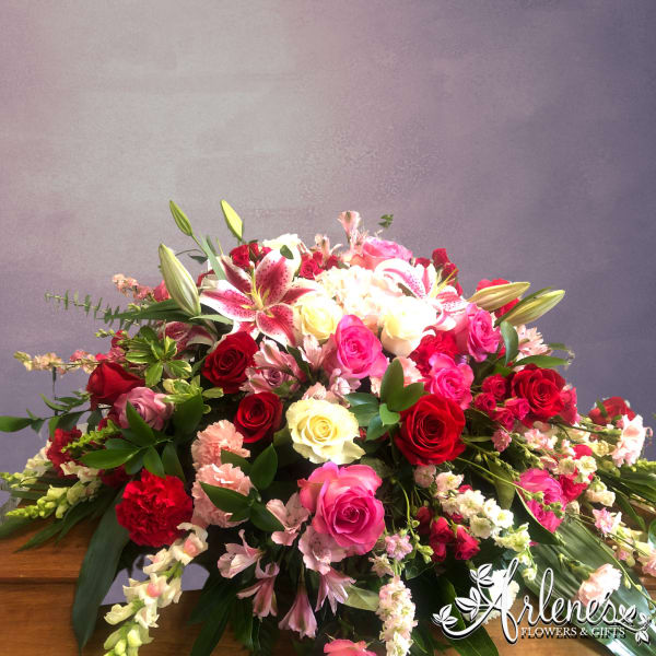 Large bouquet of red, pink, and white flowers with lilies and roses