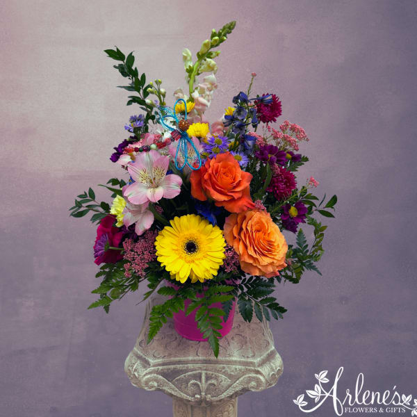 Colorful mixed flower arrangement in a pink container