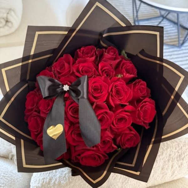 Bouquet of red roses wrapped in black paper with a ribbon