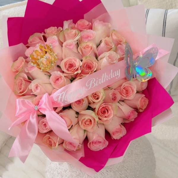 Bouquet of pale pink roses wrapped in pink paper with a birthday ribbon