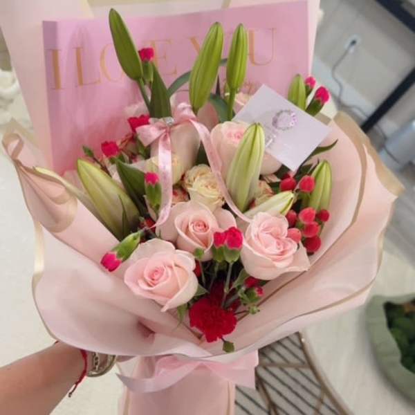 Pink bouquet with roses, lilies, and carnations wrapped in pastel paper
