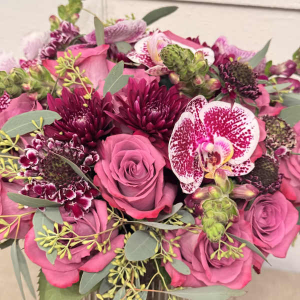 Pink roses and orchids with dark burgundy blooms in a bouquet