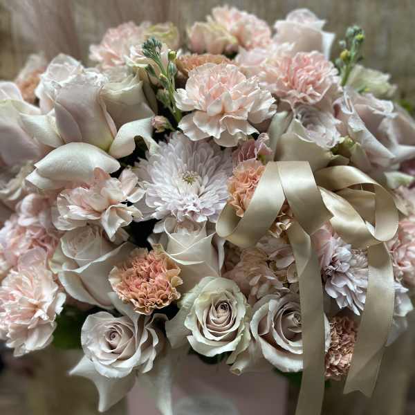 Blush and ivory bouquet of roses, carnations, and mums in a pink hatbox