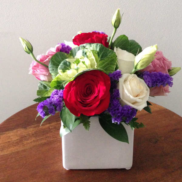 Bouquet of red, white, pink, and purple flowers in a white square vase