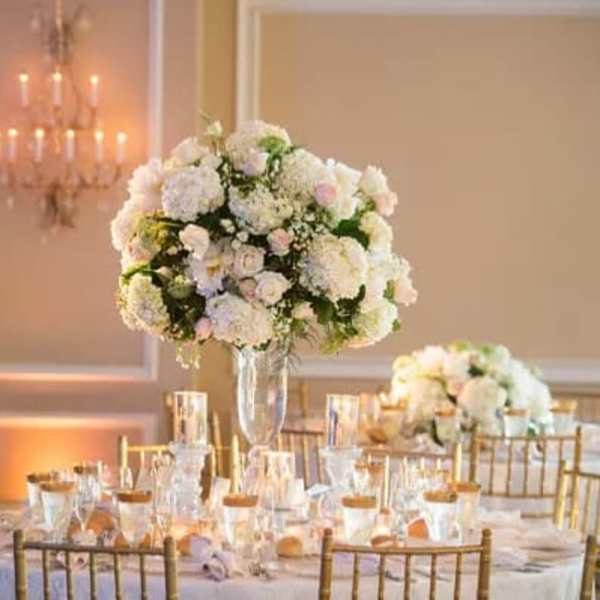 Tall white floral centerpiece in a clear vase on a banquet table