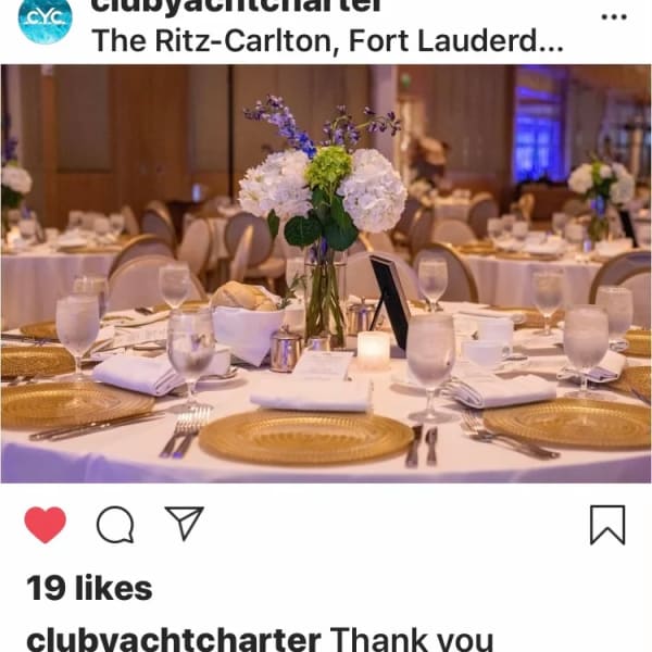 Round banquet table with a white floral centerpiece and gold chargers