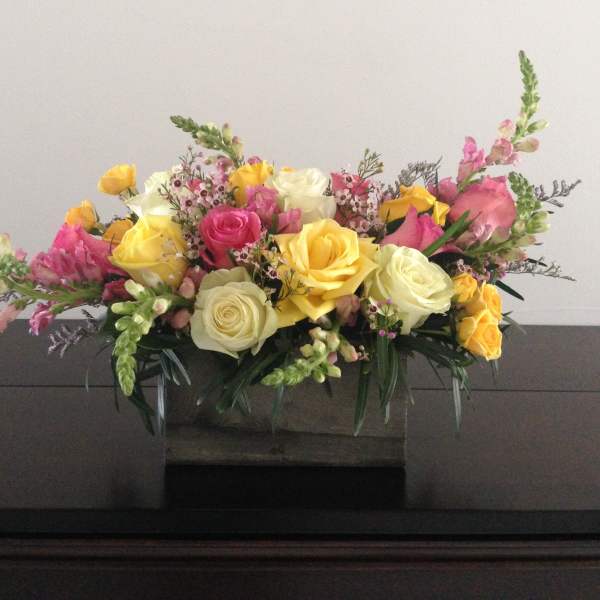 Mixed bouquet of yellow, pink, and white roses in a low container