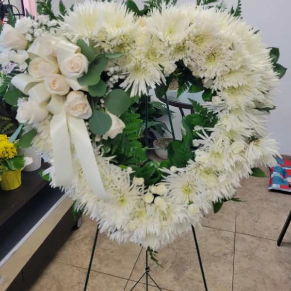 White floral funeral wreath with roses and chrysanthemums on a stand